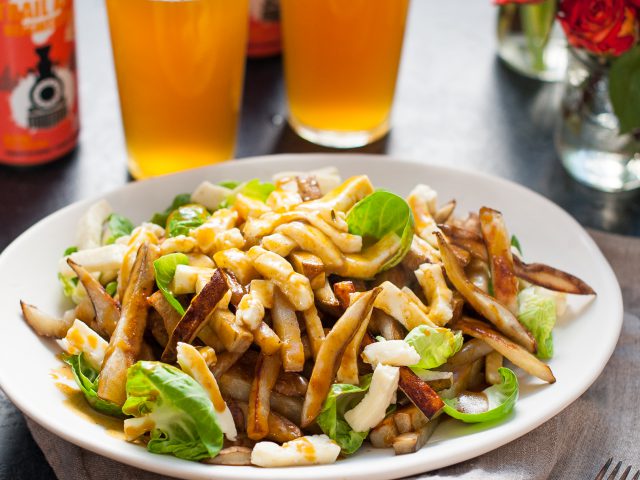 A plate of poutine garnished with brussels sprout leaves.