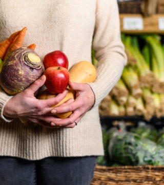 A photo of a woman holding a handful of local produce