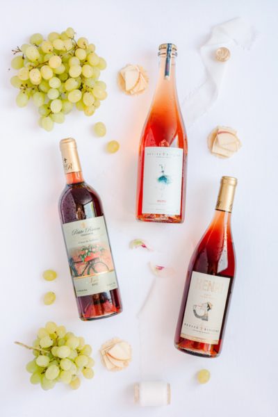 A photo of three bottles of Petite Riviere Rose wines, surrounded by decorations