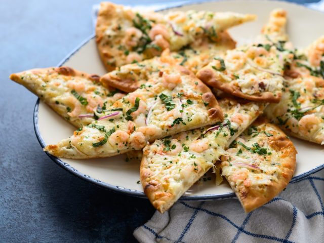 several slices of shrimp flatbread sit on a white plate