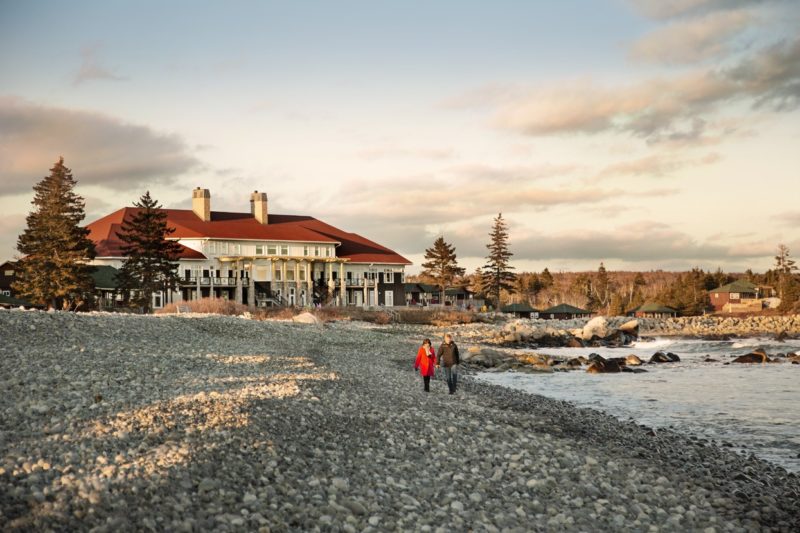 couple walks along the beach in winter in front of White Point Beach Resort