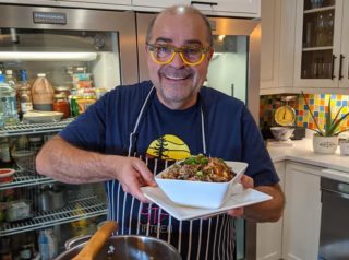 Alain Bosse the Kilted chef holding a white bowl of chili with a large pot in front