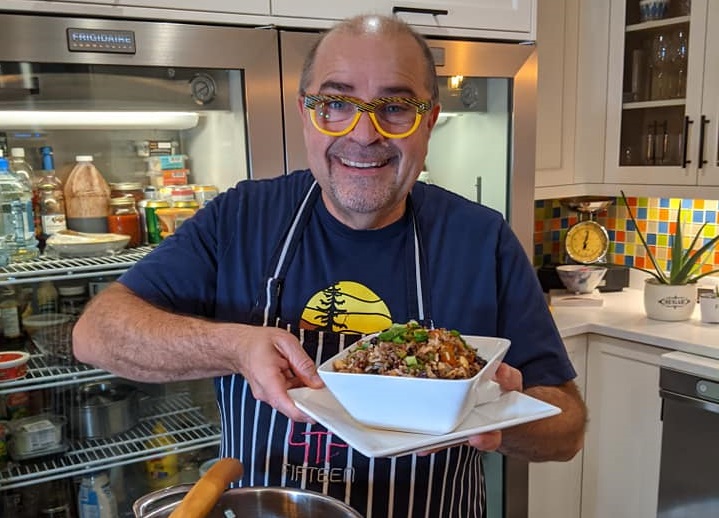 Alain Bosse the Kilted chef holding a white bowl of chili with a large pot in front