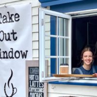 Women holds coffee out the take out window at the barn Coffeehouse