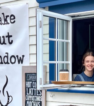 Women holds coffee out the take out window at the barn Coffeehouse