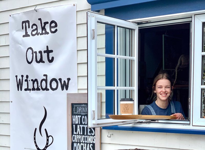 Women holds coffee out the take out window at the barn Coffeehouse