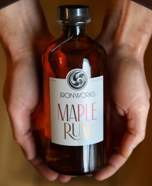 Bottle of Ironworks maple rum is held in the palm of someone's hands
