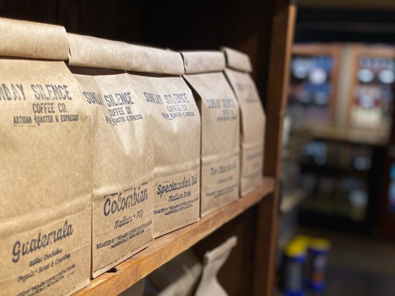 Bags of Sunday Silence Coffee Company line up diagonally on a wooden shelf