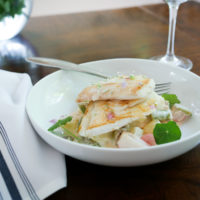 two pieces of haddock are placed in a white dish with a napkin to the left.