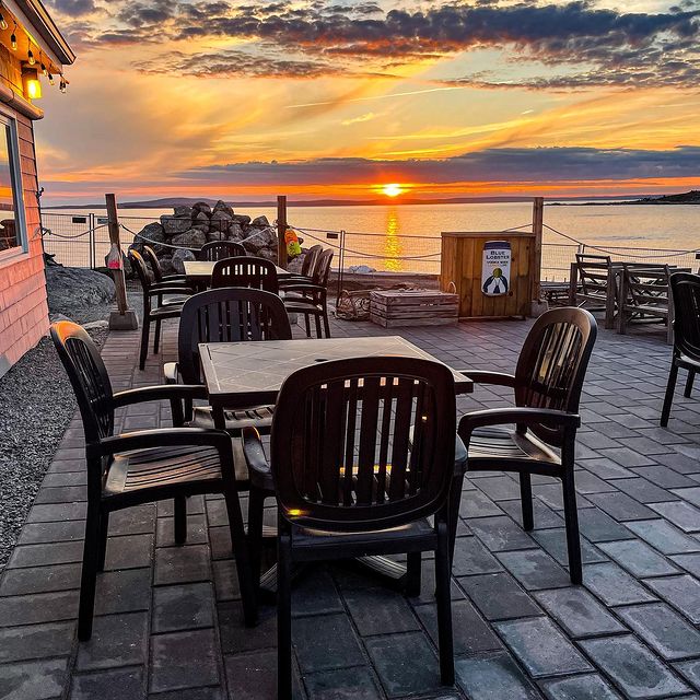 Chairs and tables on a patio overlooking the water. 