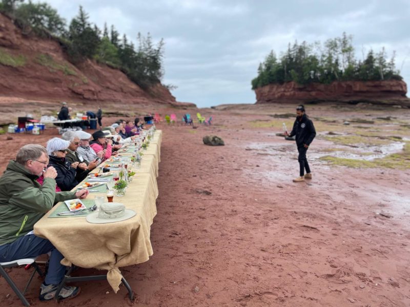 A large group of people sit on a long table at Burncoat head for dining on the ocean floor