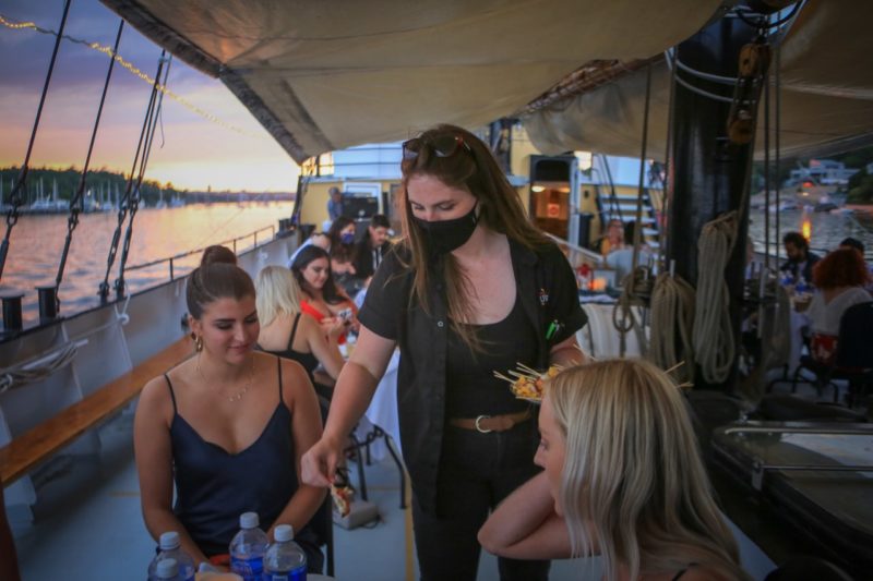 two women are greeted by a server on a tall ship