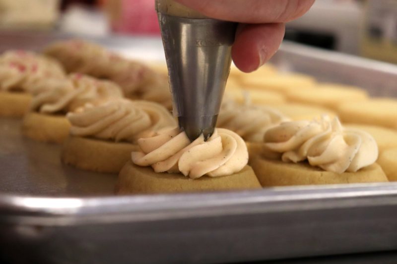 A person icing shortbread cookies.