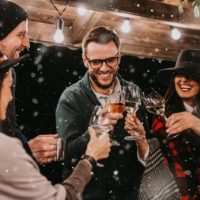 six people cheers while little spinkles of snow fall in the evening outside