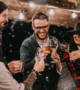 six people cheers while little spinkles of snow fall in the evening outside