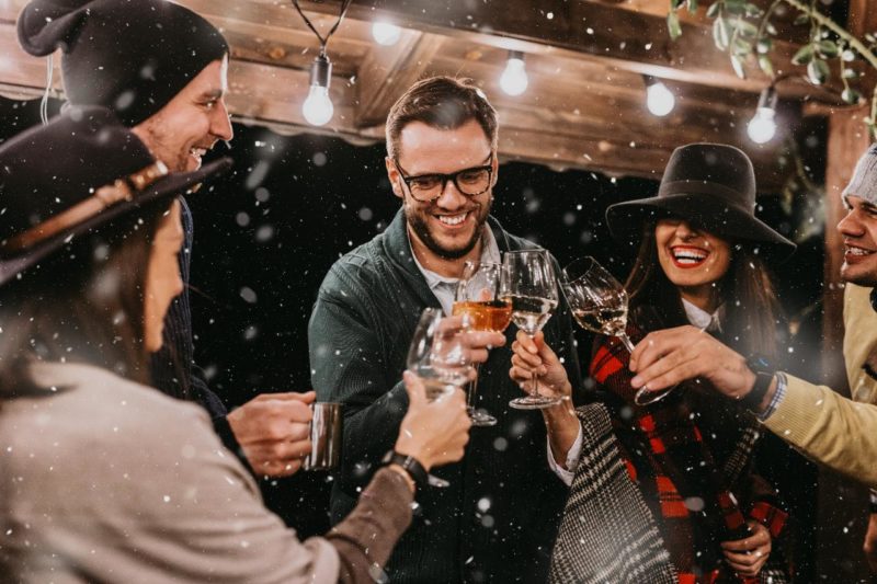six people cheers while little spinkles of snow fall in the evening outside 