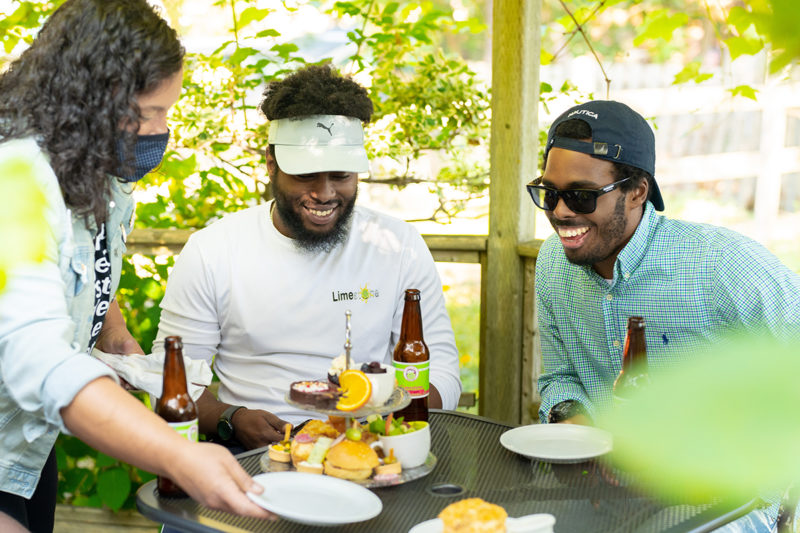 two people are served outside at a tabled by another person