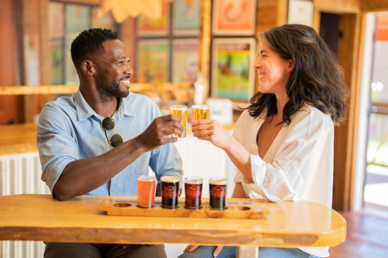 two people cheers a small flight of beer inside Tatamagouche Brewing