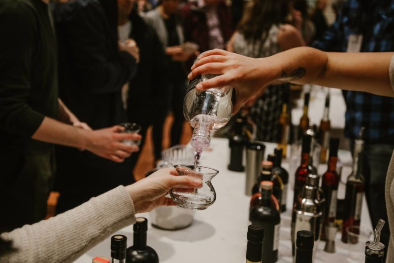 A hand pours a spirit into a tasting glass 