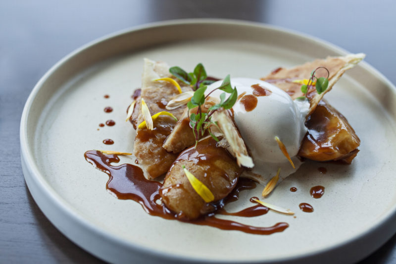 white plate with a tasting item on it. there is a brown sauce. 
