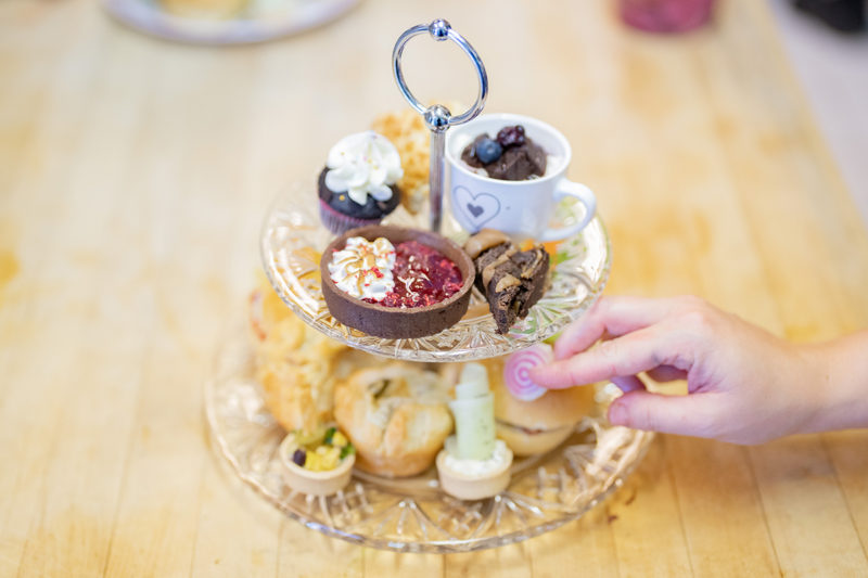 A tiered tray of treats with a hand reaching for one of them. 