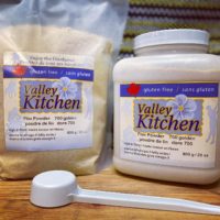 one bag and one plastic container flax powder sit on a wooden table