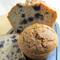 blueberry muffins. one is whole, one is cut in the middle