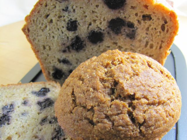 blueberry muffins. one is whole, one is cut in the middle