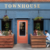 Two groups of people sit on the patio outside at the Townhouse