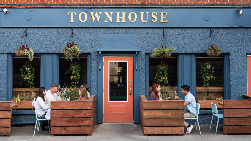 Two groups of people sit on the patio outside at the Townhouse