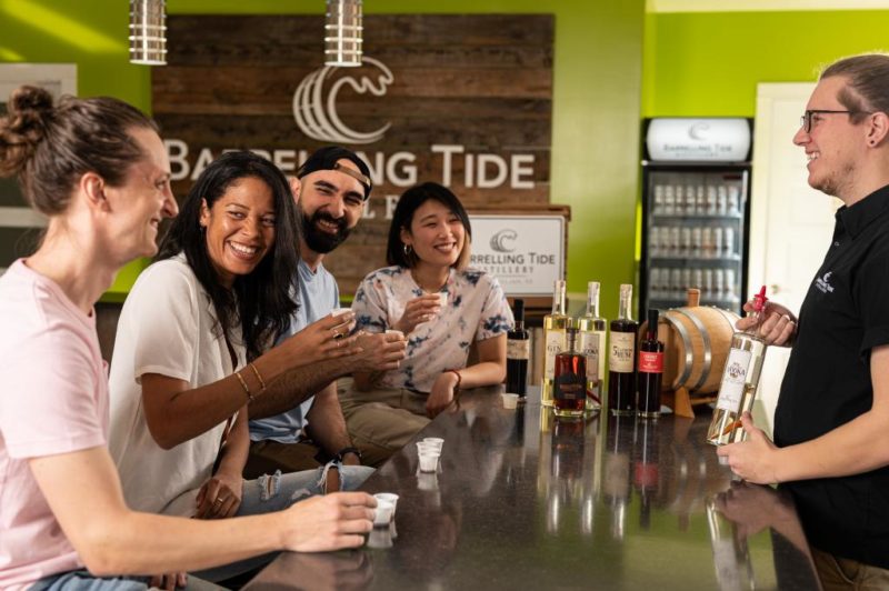 Several people enjoy samples in tiny sample cups at Barelling Tide Distillery. 