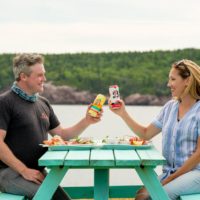 two people cheers beverages on a picnic table at the Chowder House