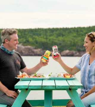 two people cheers beverages on a picnic table at the Chowder House