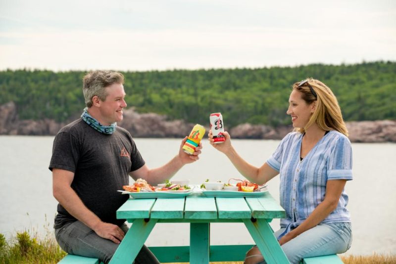 two people cheers beverages on a picnic table at the Chowder House 