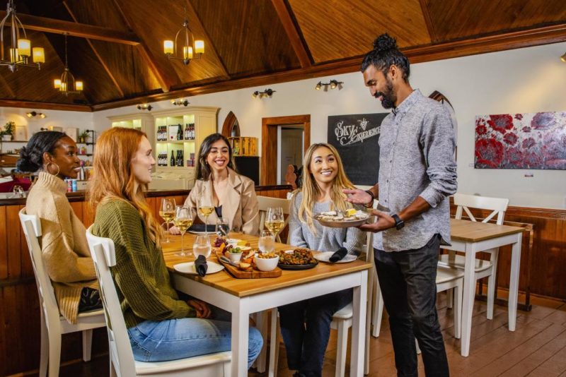 Three people enjoy food and drinks while being served at Avondale Sky winery