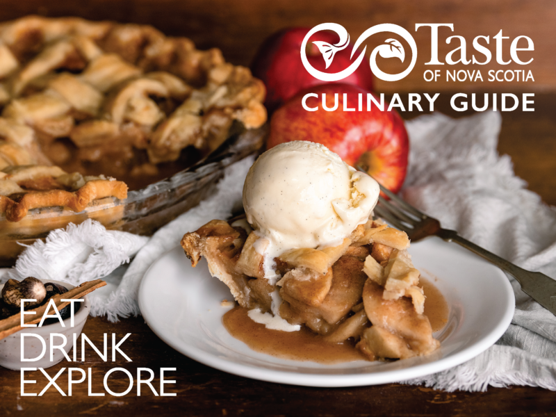 A photo of the 2023 Taste of Nova Scotia Culinary Guide. The cover image features a traditional apple pie, with a slice cut out and served on a plate with ice cream on top.
