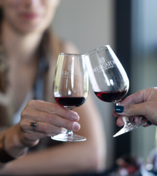 A photo of two people doing a cheer with samples of a red wine from Mercator Vineyards.
