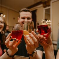 A photo of three people clinking their glasses together in cheers at the 2022 Ciders and Sliders event.