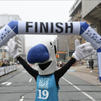 The Blue Nose Marathon mascot under the finish line banner.