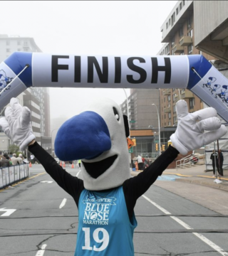 The Blue Nose Marathon mascot under the finish line banner.