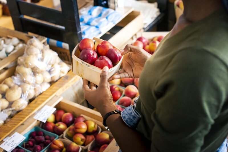 A photo of a person's hands holding apples at Uprooted Market & Cafe