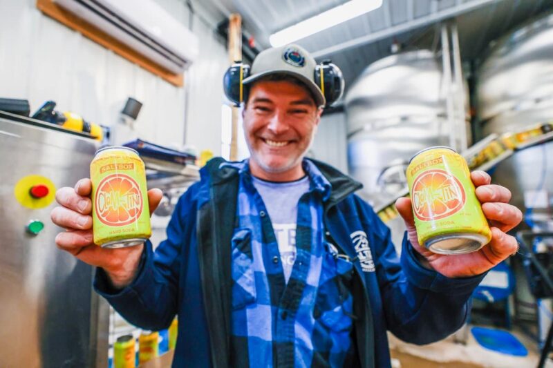 Saltbox employee holding new cans of Clem-tini Hard Soda