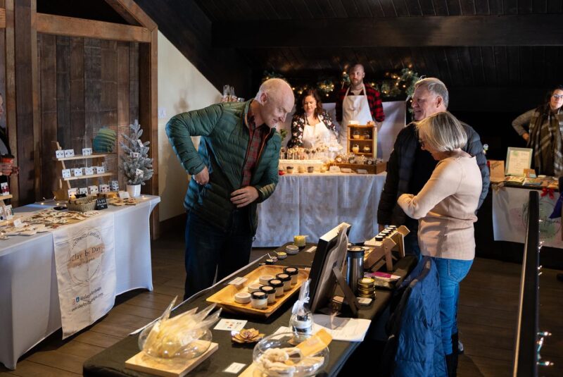 People at Jost Holiday Market look at a vendor's booth.