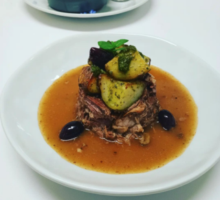 photo of fancy meal, zucchini chunks on top of juicy meat on a plate 