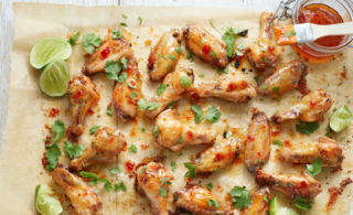 Photo of Galloping Cows Hot Jalapeño Pepper Jelly Glazed Chicken Wings spread out on a baking sheet with a jar of jelly in the top right corner